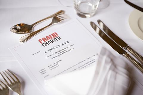 An itinerary for the Fraud Charter roundtable peeks above a napkin between a golden cutlery table set.